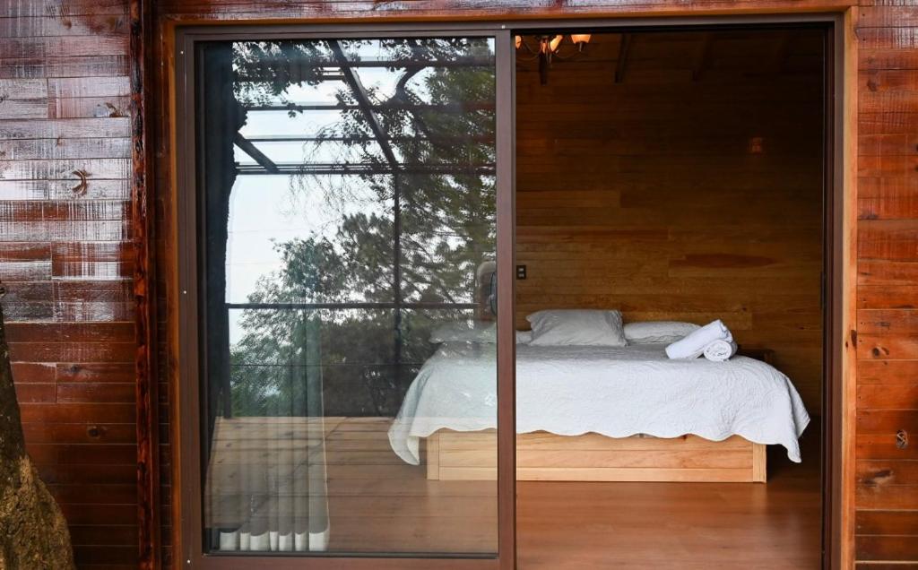 a bedroom with a bed and a large glass window at San José del Pacífico Camino al Cielo C3 in San Jose del Pacifico