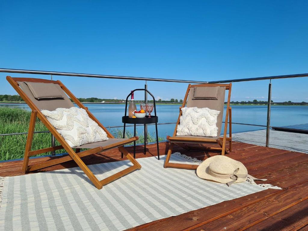 two chairs and a table on a deck near the water at A comfortable house on the water for 5 people in Łazy