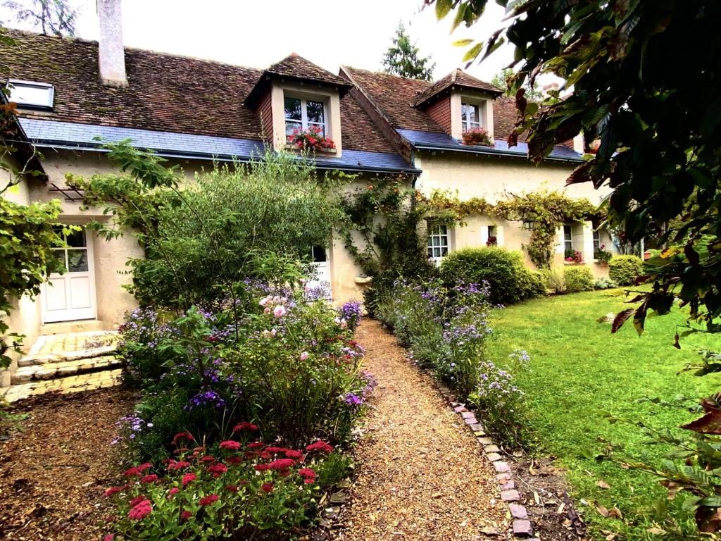 un jardin devant une maison avec des fleurs dans l'établissement Ancien logis familial avec parc et activités, près des Châteaux de la Loire, tout inclus, animal accepté - FR-1-381-466, à Souvigny-de-Touraine