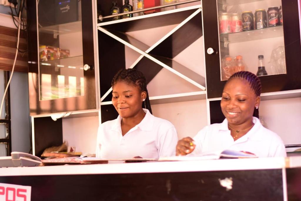 two women standing behind a counter in a kitchen at Royal Suites and Apartments in Jidu