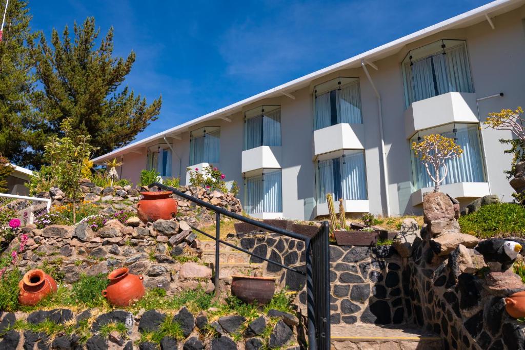 um edifício com uma parede de pedra e algumas plantas em Lake Titicaca Hotel em Puno