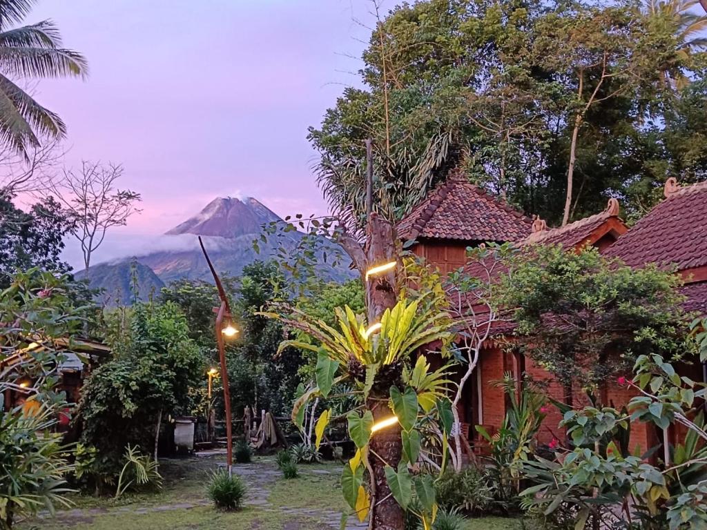 a house with a mountain in the background with lights at Villa Mak Cik in Yogyakarta