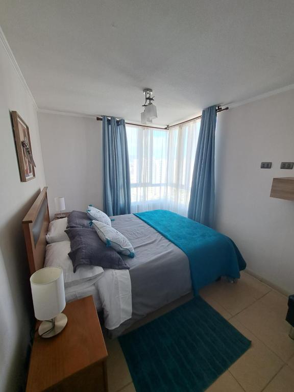 1 dormitorio con 1 cama y una ventana con cortinas azules en Marina Sol III, en Coquimbo
