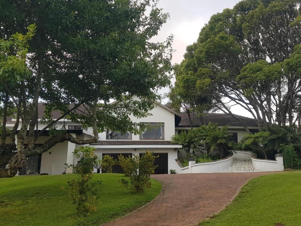 a white house with a driveway and trees at Paradise View Guesthouse in Graskop