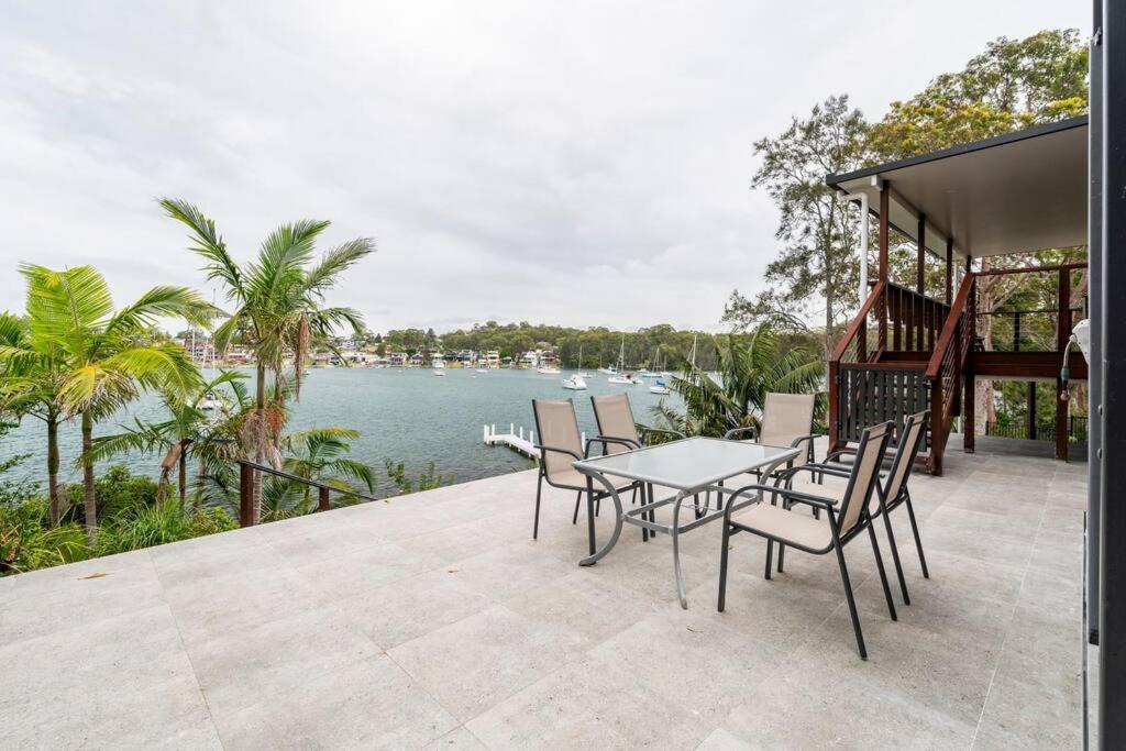 d'une terrasse avec une table et des chaises au bord de l'eau. dans l'établissement Stunning Absolute Waterfront With Private Jetty, à Fishing Point