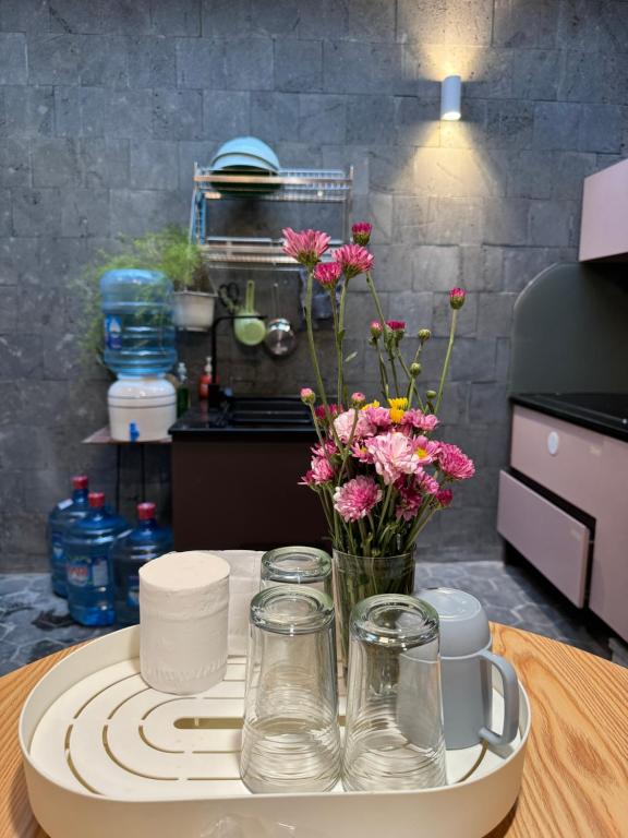 a table with a vase of flowers and glasses on it at DORI HOUSE NTL in Ho Chi Minh City