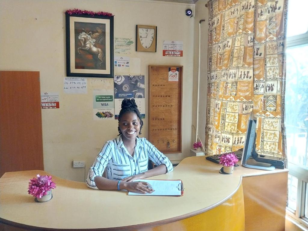 a woman sitting at a counter with a book at THE DESERT ROSE HOTEL VOI in Voi