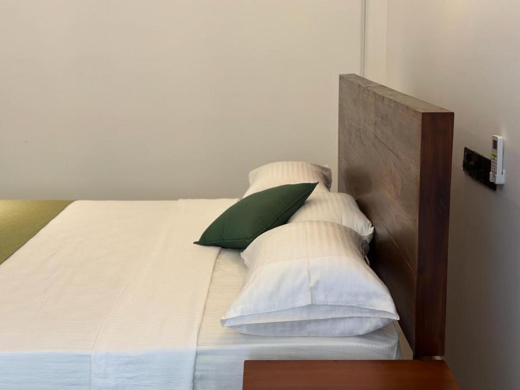 a bed with white pillows and a green pillow at Emerald Home Stay in Anuradhapura