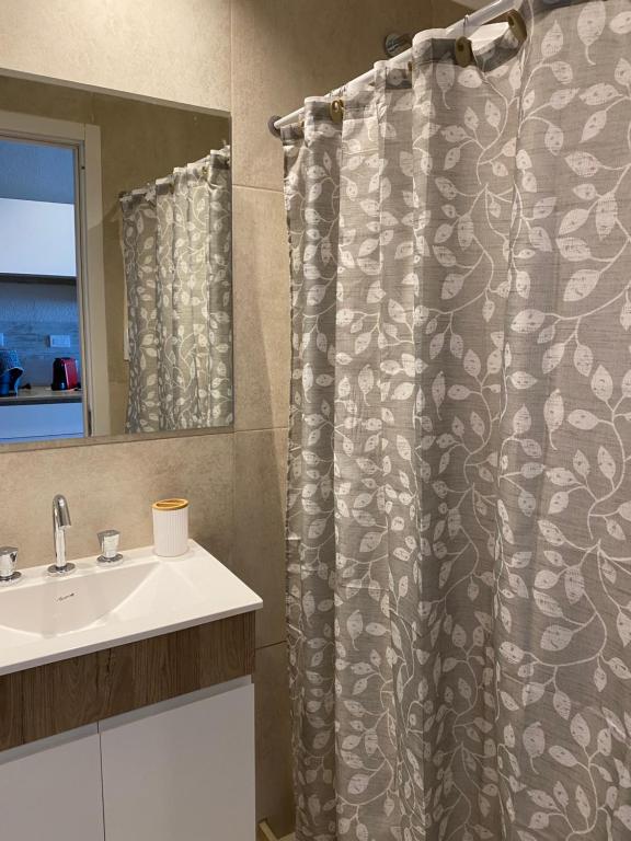 a bathroom with a shower curtain and a sink at Frente al mar con pileta in Quequén