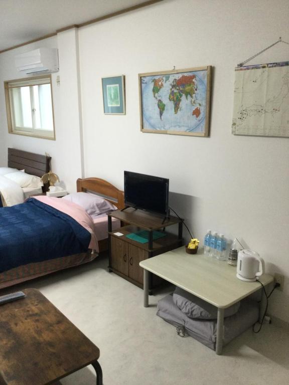 Accommodation Service B&B في ميازاكي: غرفة نوم مع سرير ومكتب مع جهاز كمبيوتر