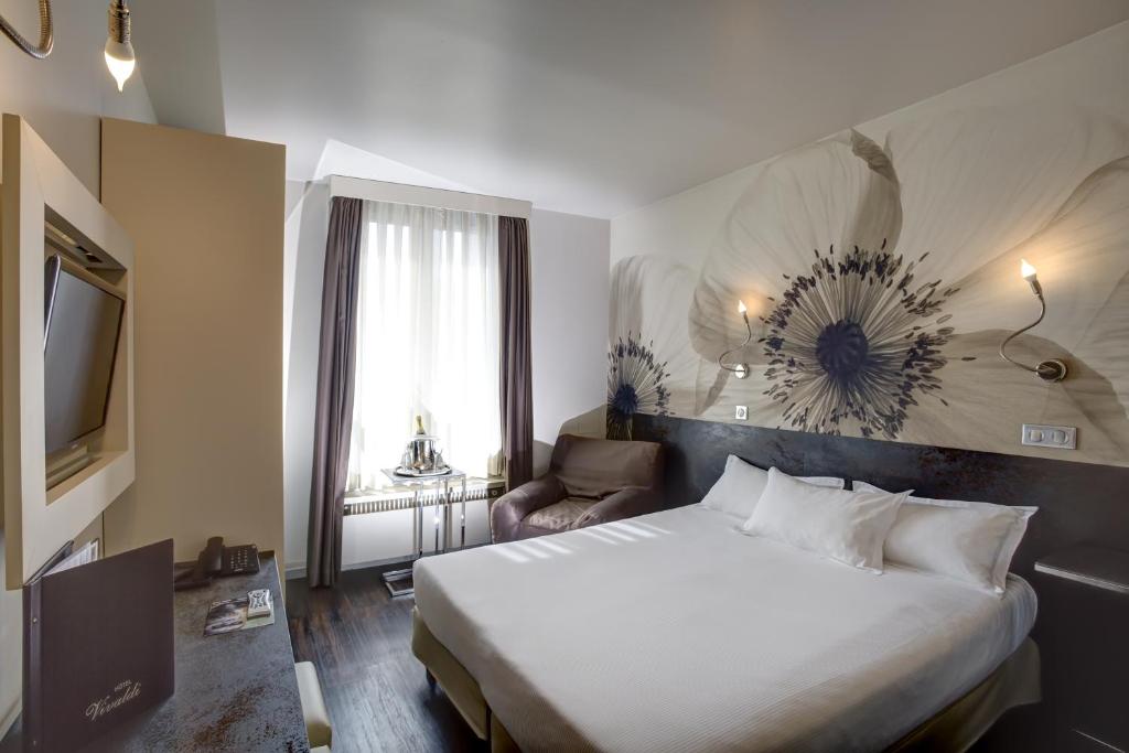 um quarto de hotel com uma cama e uma televisão em Hotel Vivaldi em Puteaux