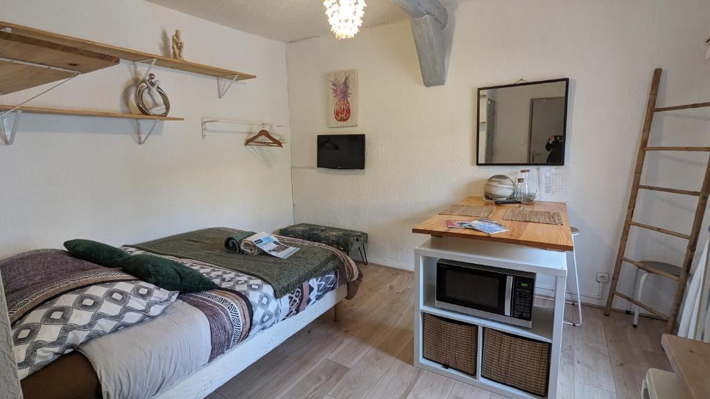 a bedroom with a bed and a desk with a microwave at STUDIO avec PARKING TOUT A PIED et CALME in Bandol
