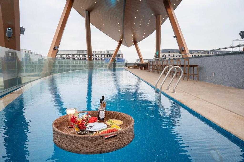- une table avec une bouteille de vin et des fruits à la piscine dans l'établissement Regal Collection House, à Dương Cảnh