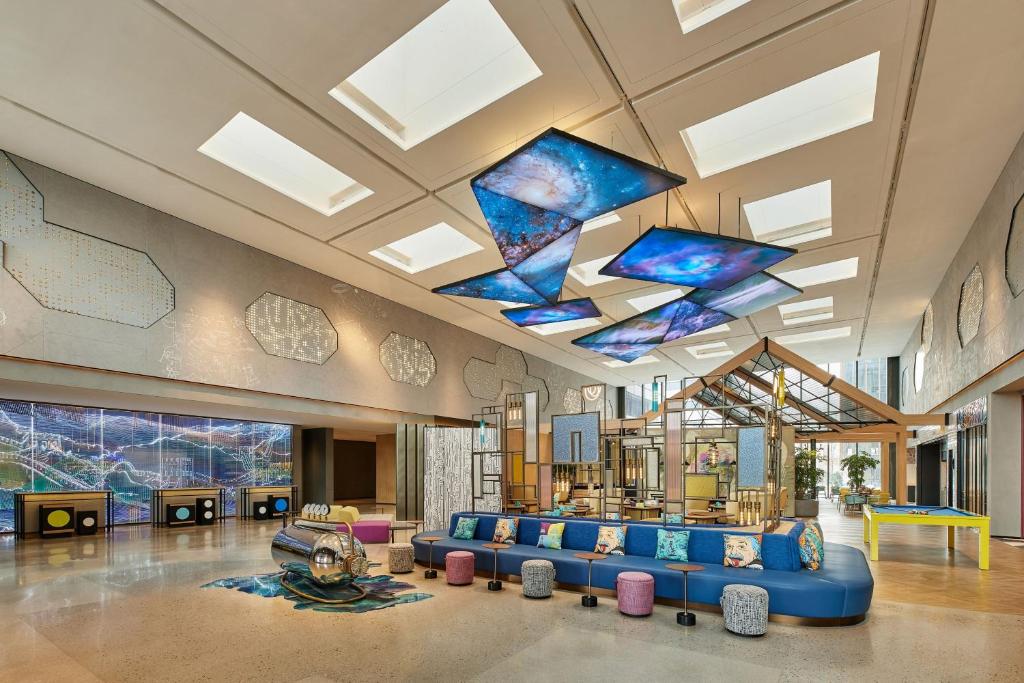 eine Lobby mit einem blauen Sofa und einigen Fenstern in der Unterkunft Aloft Beijing Huairou in Huairou