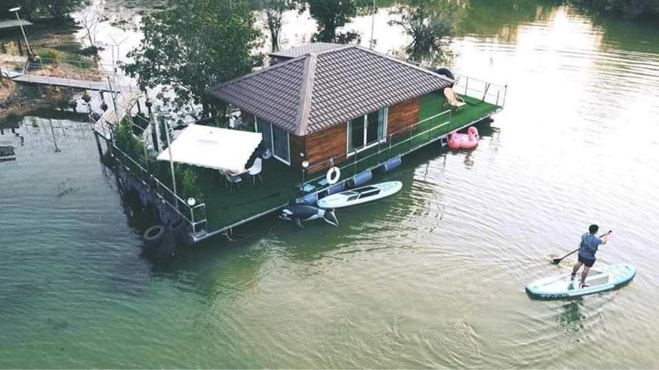 een man op een paddleboard voor een huis bij บ้านกลางโดม Baan Klang Dome in Ban Huai Hai
