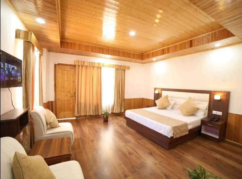 a bedroom with a bed and a couch and a tv at The king hill resort in Goa