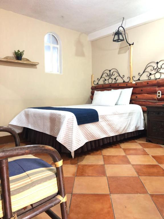 a bedroom with a bed and a chair at Casa de los Abuelos Hotel in Tecpán Guatemala