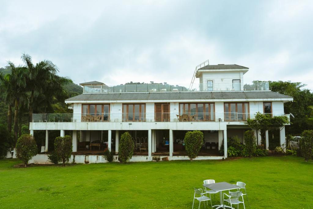 a large white house with a green yard at Pawna By Hangout Villas in Lonavala