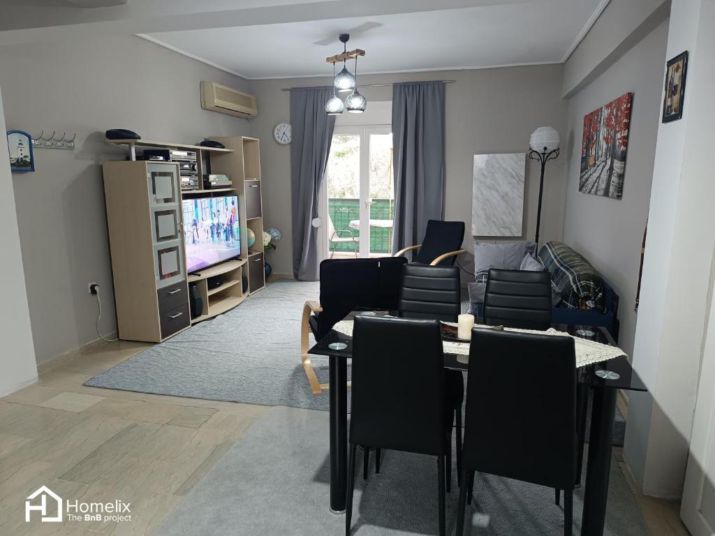 ein Wohnzimmer mit einem Tisch, Stühlen und einem TV in der Unterkunft Άνετο και ήσυχο διαμέρισμα με θέα in Chalkida