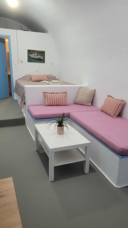 two beds with pink cushions and a table in a room at Kamaraki Aroniadika in Kythira