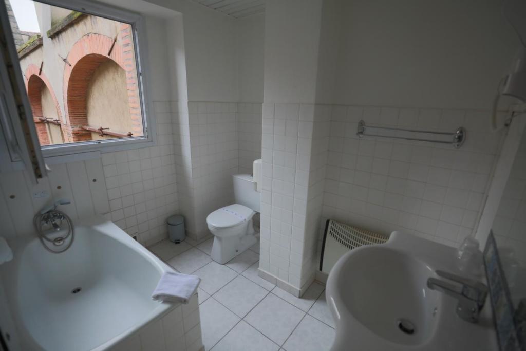 a bathroom with a sink and a tub and a toilet at Hotel Wilson Square in Toulouse