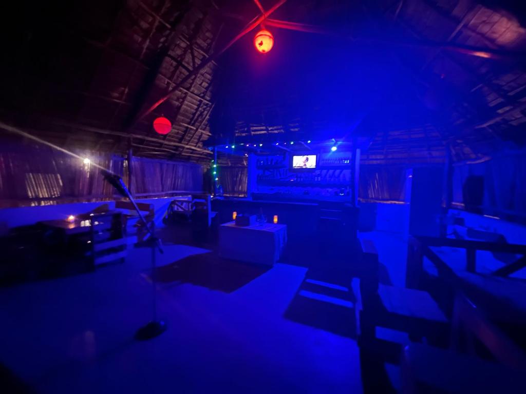 New Dindini Lodge في كيليندوني: غرفة مظلمة مع أضواء زرقاء وطاولات وكراسي