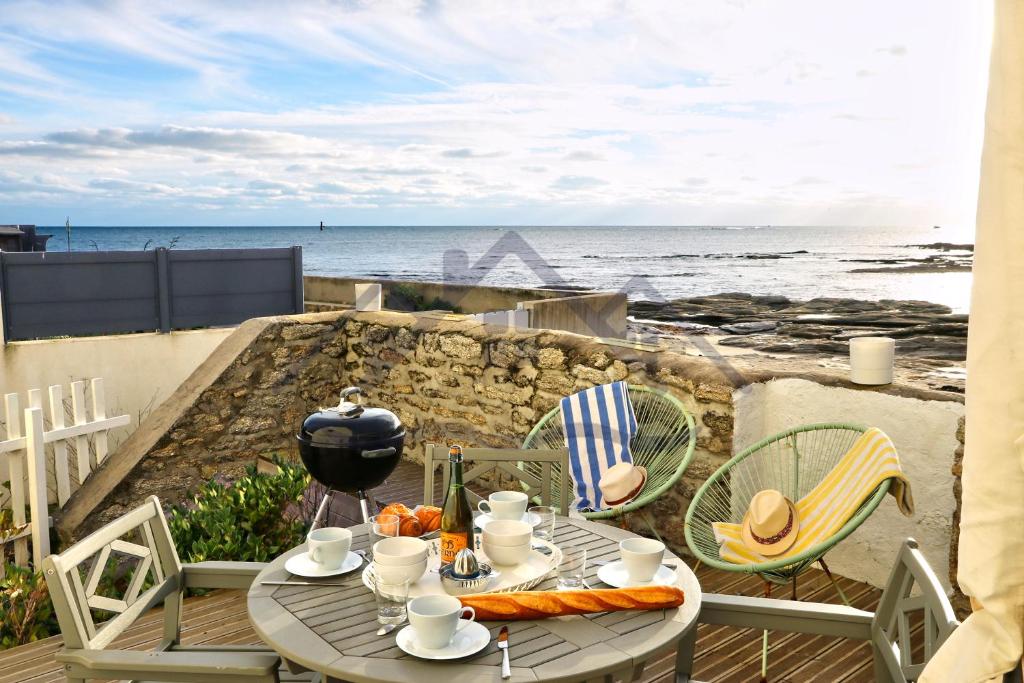 d'une table et de chaises sur un balcon donnant sur l'océan. dans l'établissement LocaLise - M4 - La maison de la pointe de Lechiagat - Accès à deux pas d'une terrasse vue mer privative - Wifi inclus - Draps inclus - Animaux bienvenus, à Tréffiagat