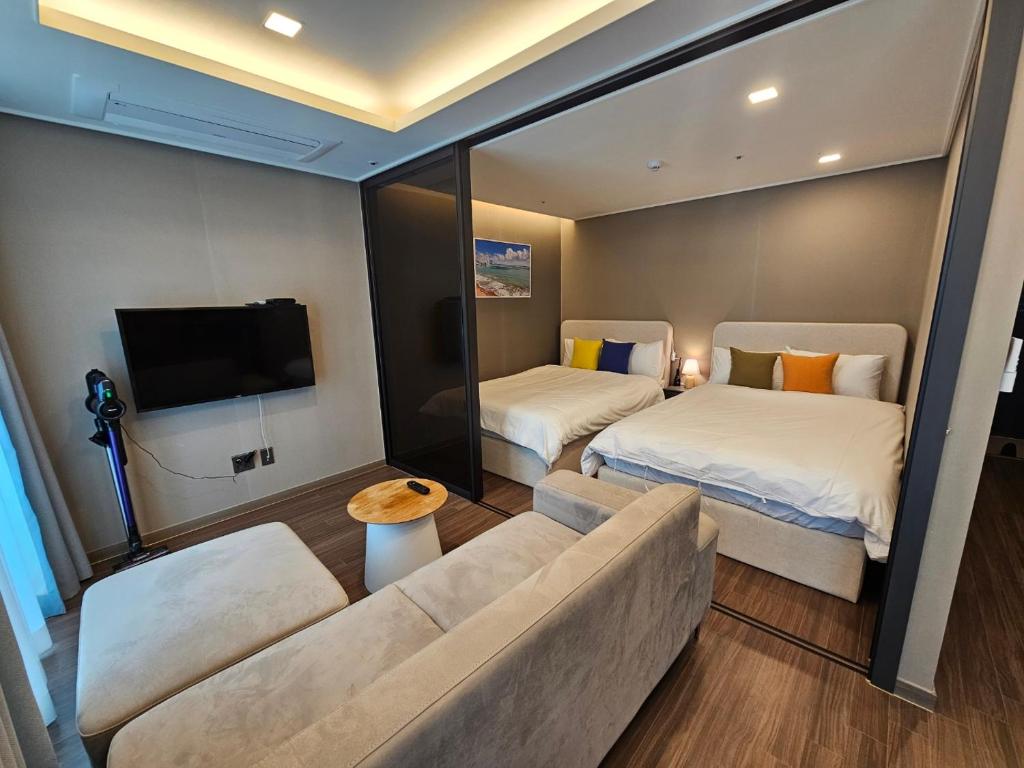 sala de estar con sofá, cama y TV en Gunamro Hotplace 3min Haeundae beach, en Busan