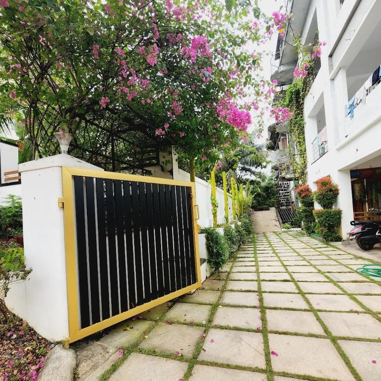 a gate on a sidewalk next to a building with pink flowers at UPPU HOMESTAY in Mulappilangād