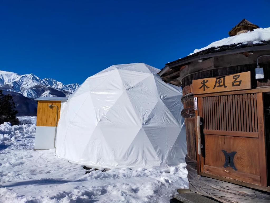 a large tent in the snow next to a building at G-4 Gramping Sauna 白馬森のわさび農園 in Hakuba