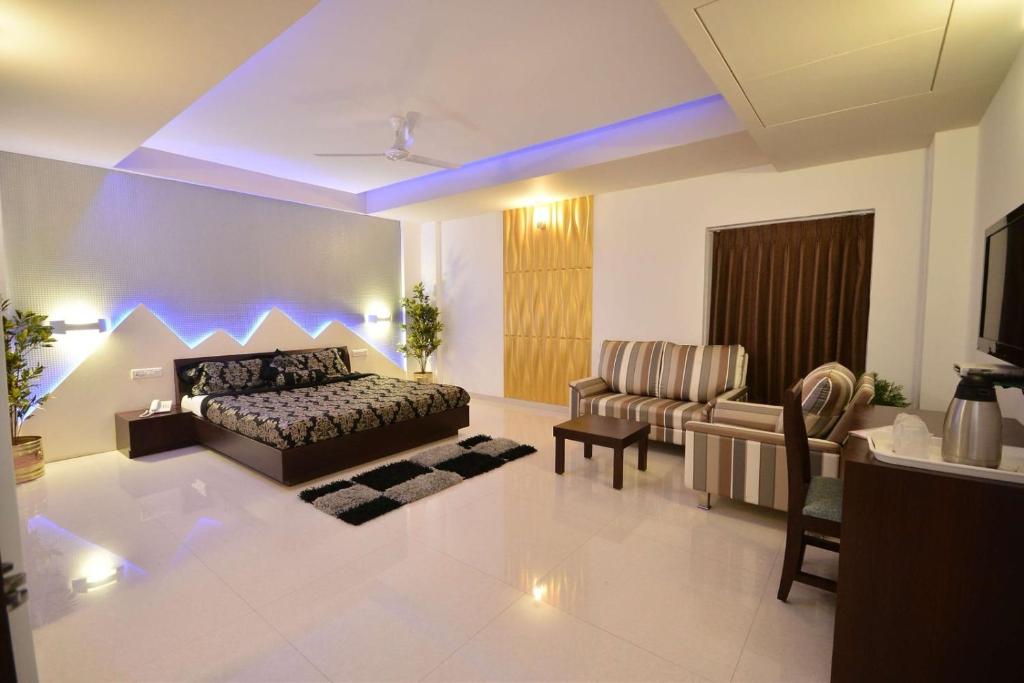 HOTEL THE SENTOSA في راجكوت: غرفة نوم مع سرير وغرفة معيشة مع أريكة