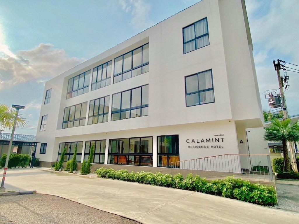 - un grand bâtiment blanc avec un panneau dans l'établissement Calamint Residence Hotel ( คาลามิ้นท์), à Chumpon