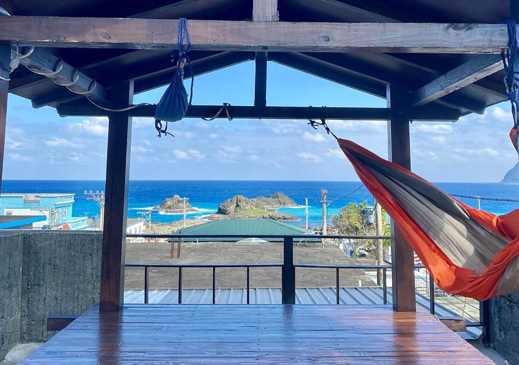 a hammock on a deck with the beach in the background at Ahdu Backpacker Inn B&B in Lanyu
