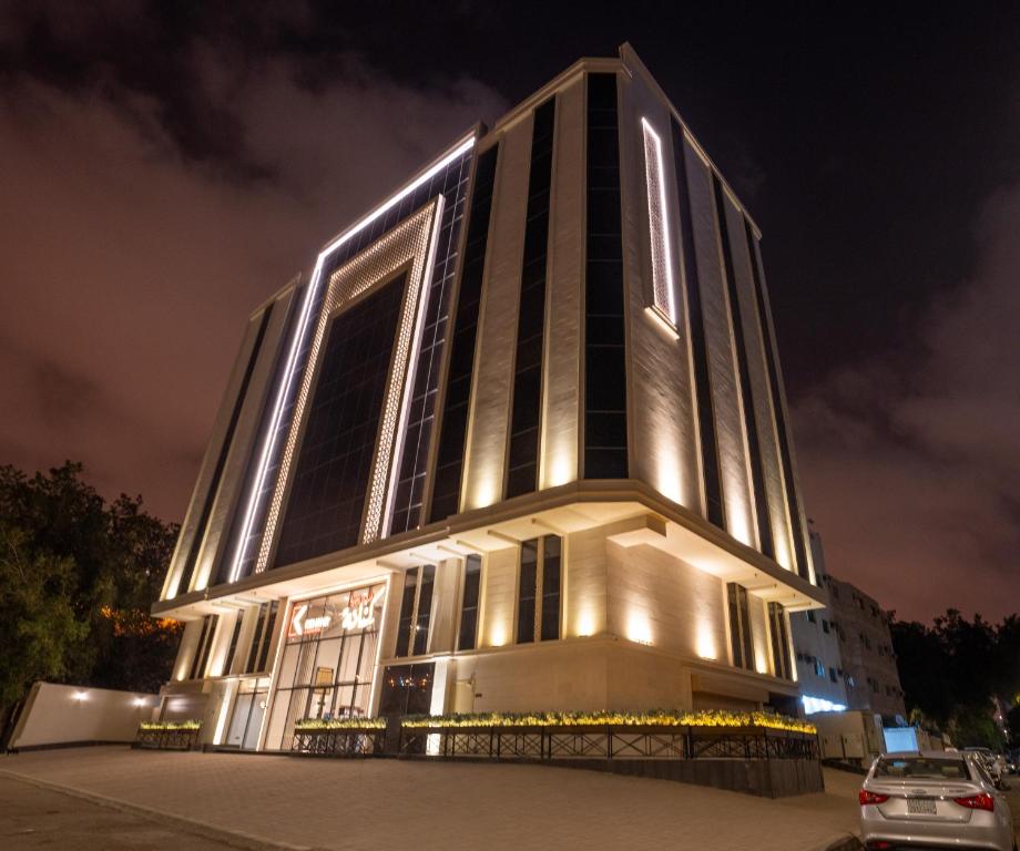 um edifício alto com luzes acesas à noite em فندق كنانة العزيزية من سما em Meca