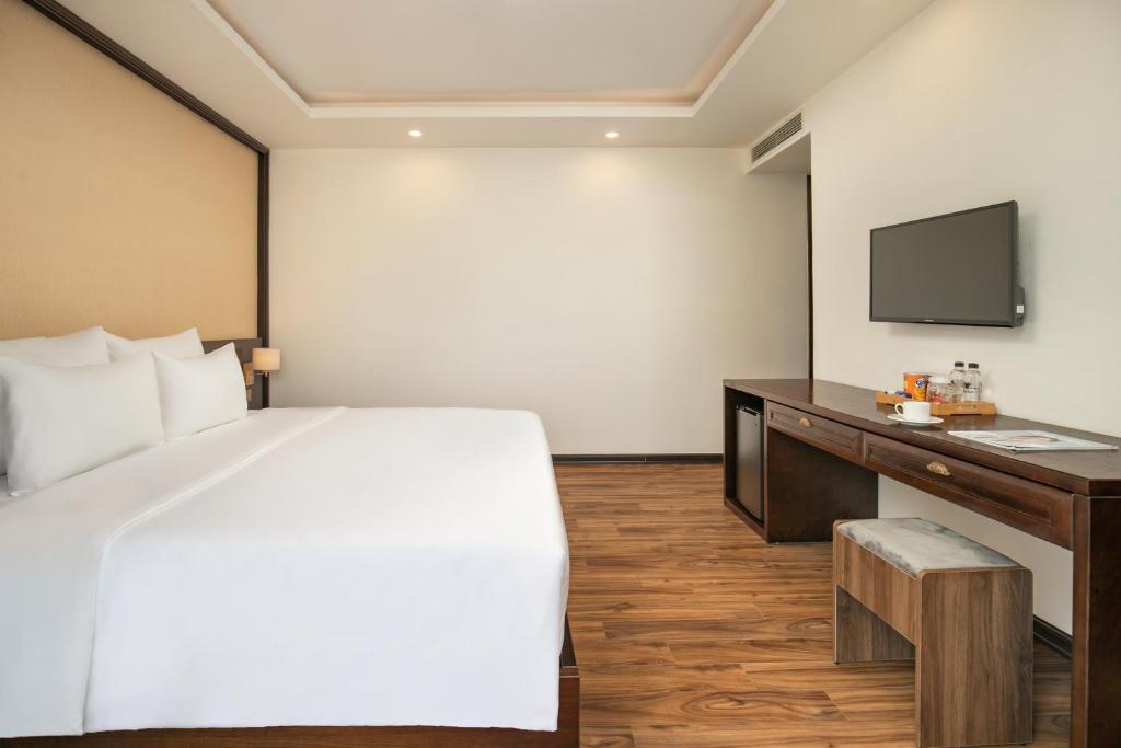 a bedroom with a bed and a desk and a tv at Palazzo Boutique Hotel in Danang