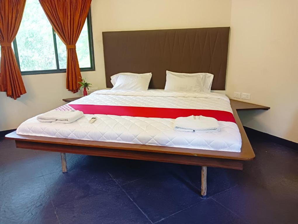 Elle comprend un grand lit avec des draps blancs et des serviettes. dans l'établissement Smiley Resorts, à Auroville