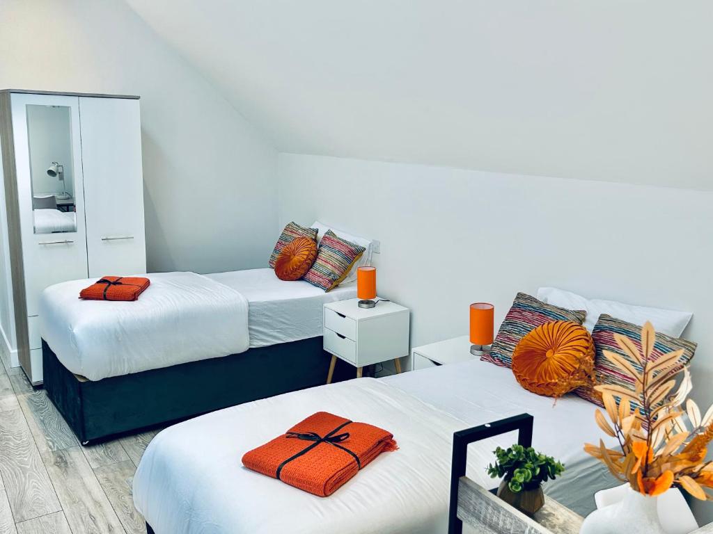 two beds with orange pillows in a room at Luxury Town Centre House, Faversham in Faversham