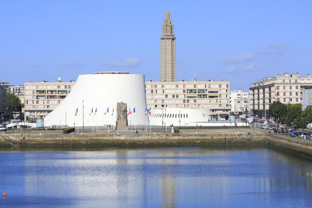 un grande edificio bianco accanto a un corpo d'acqua di Petit studio plage Le galet bleu a Le Havre