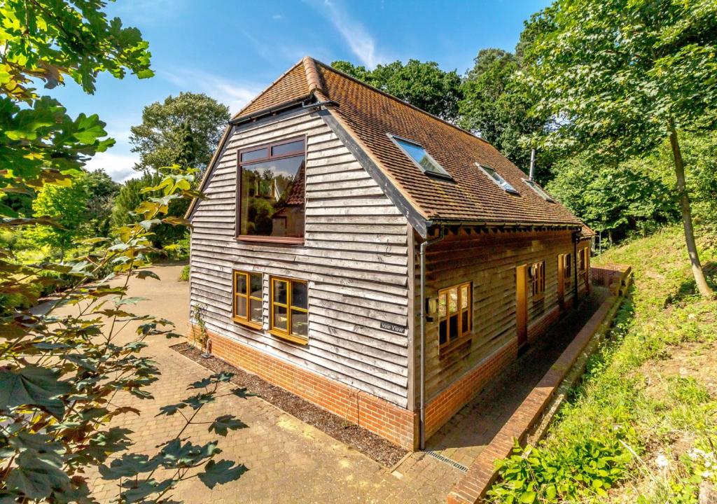 uma pequena casa de madeira num campo com árvores em Vale View em Hollesley