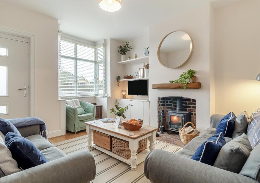 a living room with two couches and a fireplace at Seascape Cottage in Reydon