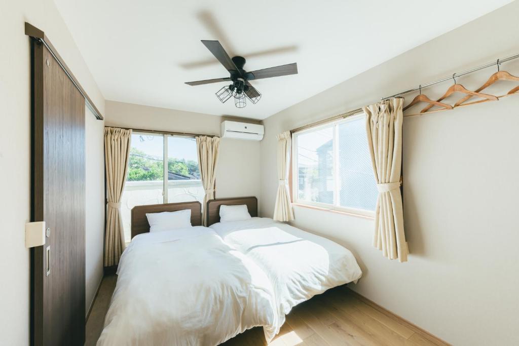 een slaapkamer met 2 bedden en een plafondventilator bij guesthouse SHIBAFU in Kamakura