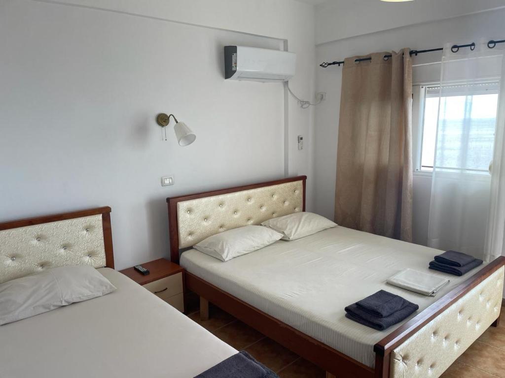 due letti in una piccola stanza con una finestra di Guesthouse Mateo a Dhërmi