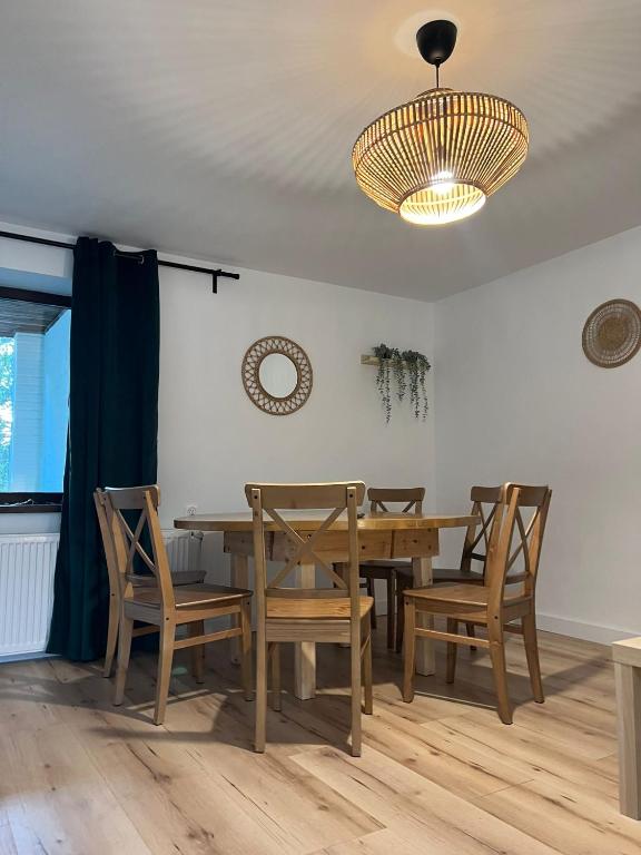 a dining room with a table and chairs and a chandelier at Apartament Jeziorna in Ocypel
