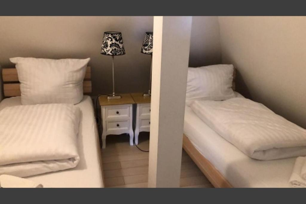 two twin beds in a room with a night stand at Ferienwohnung 20 im süßen Stadtkern von Sasel in Hamburg