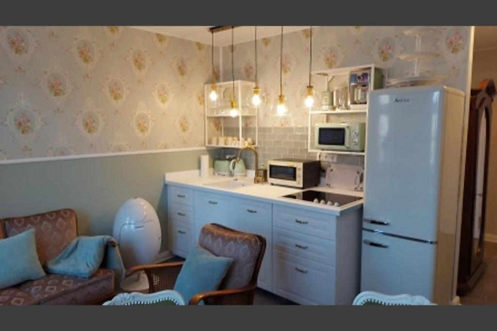 eine Küche mit einem Kühlschrank, einem Sofa und Stühlen in der Unterkunft Ferienwohnung 24 am Saseler Markt hochwertig renoviert in Hamburg
