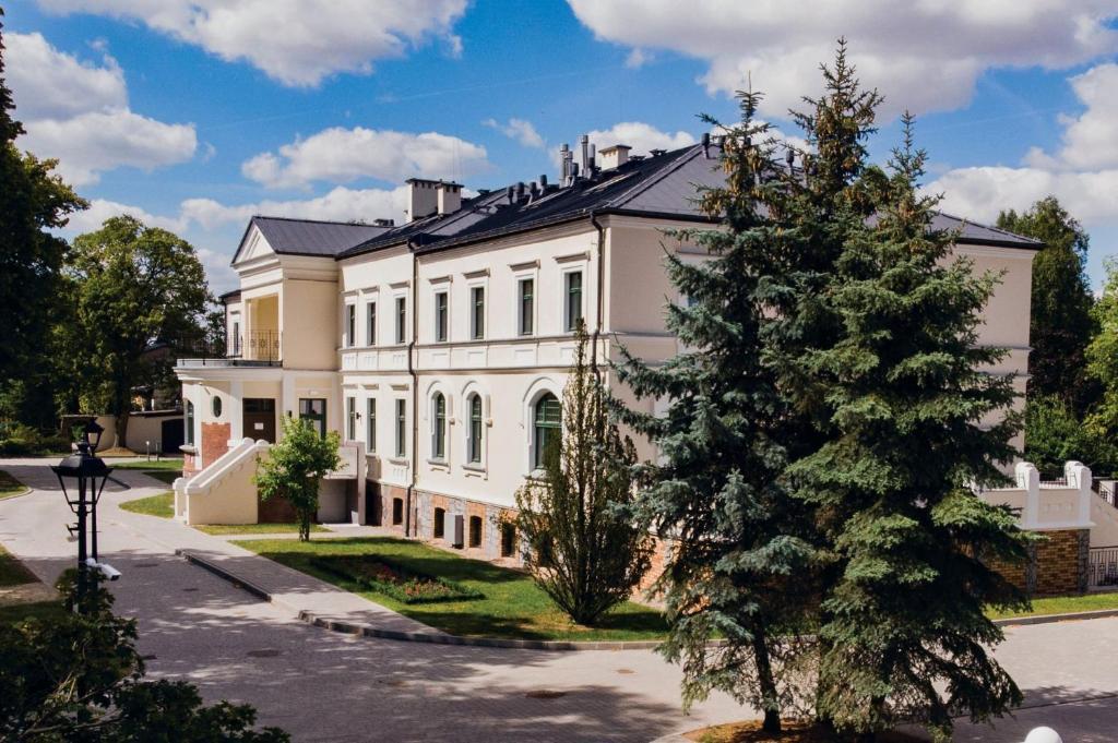 una gran casa blanca con un árbol delante en Dwór Skrzynki, 