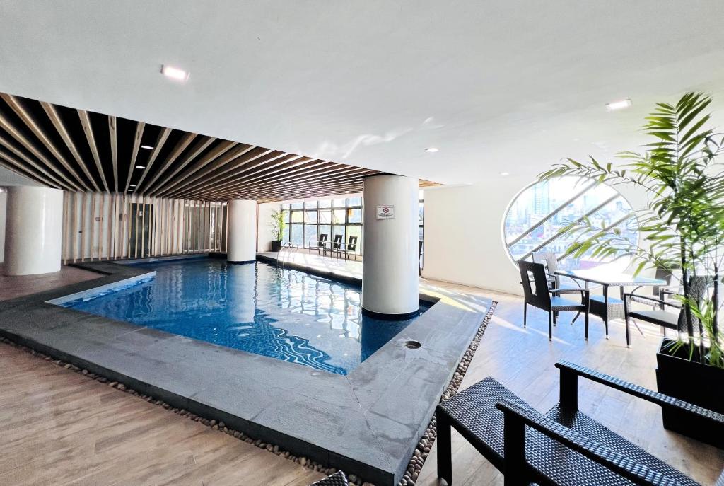 宿霧市的住宿－Sarrosa International Hotel and Residential Suites，游泳池位于带桌椅的房间