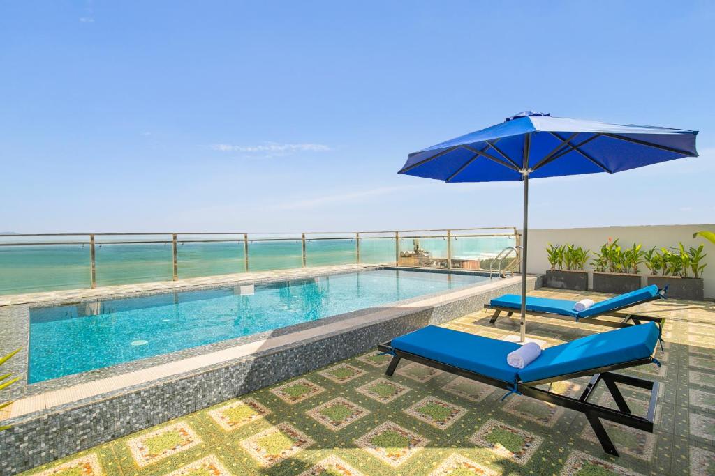a swimming pool with two chairs and an umbrella at Palazzo Boutique Hotel in Danang