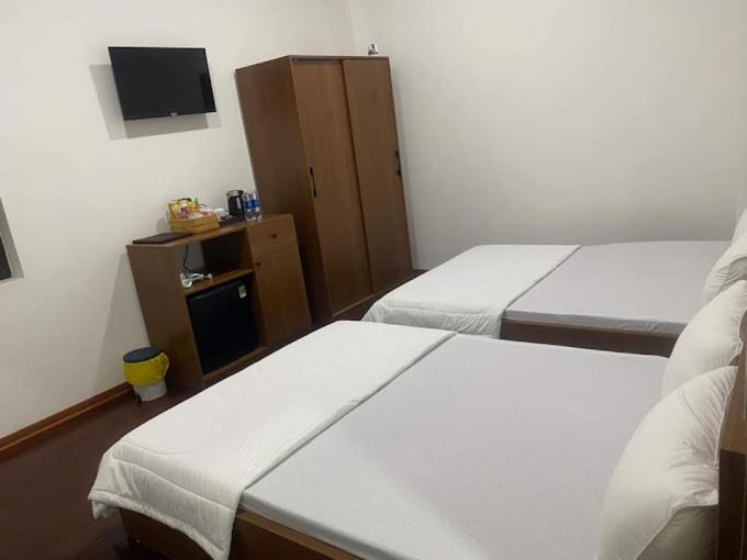 ein Hotelzimmer mit 2 Betten und einem TV in der Unterkunft NGOC PHUNG HOTEL in Ban Blech