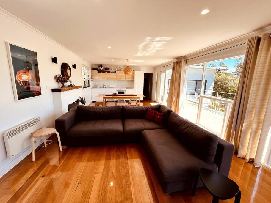 a living room with a brown couch and a table at The Coles Bay Shack - Freycinet in Coles Bay